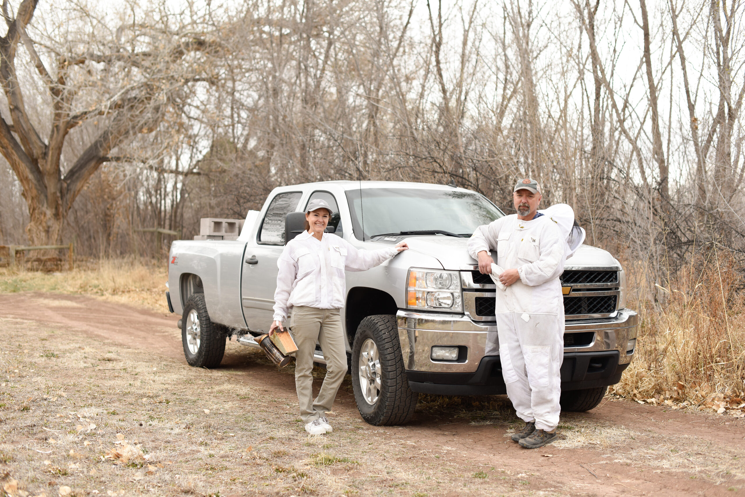 Two men standing next to a truck in the woods.